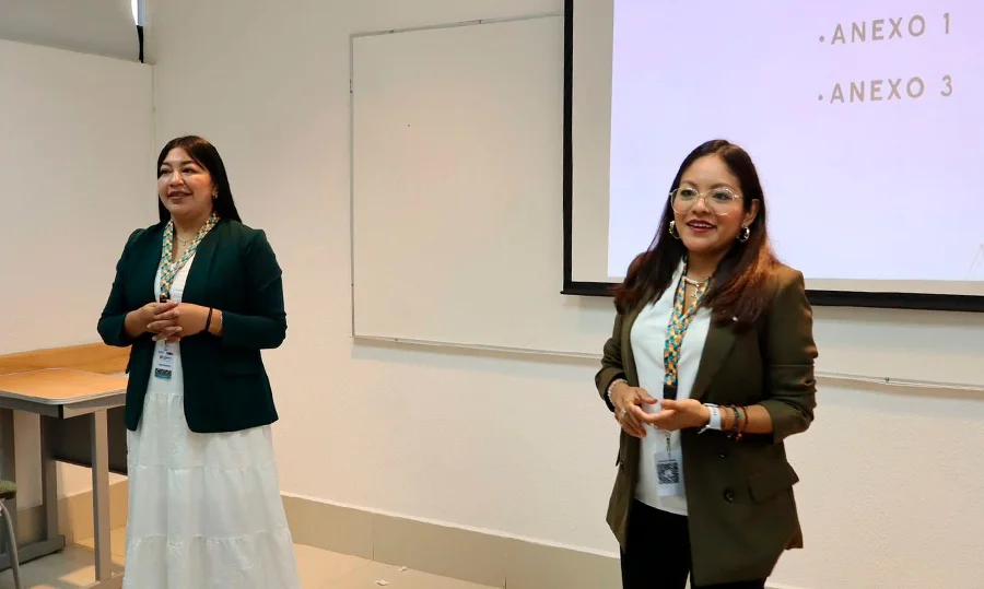 Una taza de café descansa sobre una mesa de madera entre una tablet y un teléfono inteligente que muestran una página web. Al fondo hay documentos apilados y una impresora."