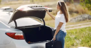 Mujer guarda una maleta en el maletero de un auto antes de viajar