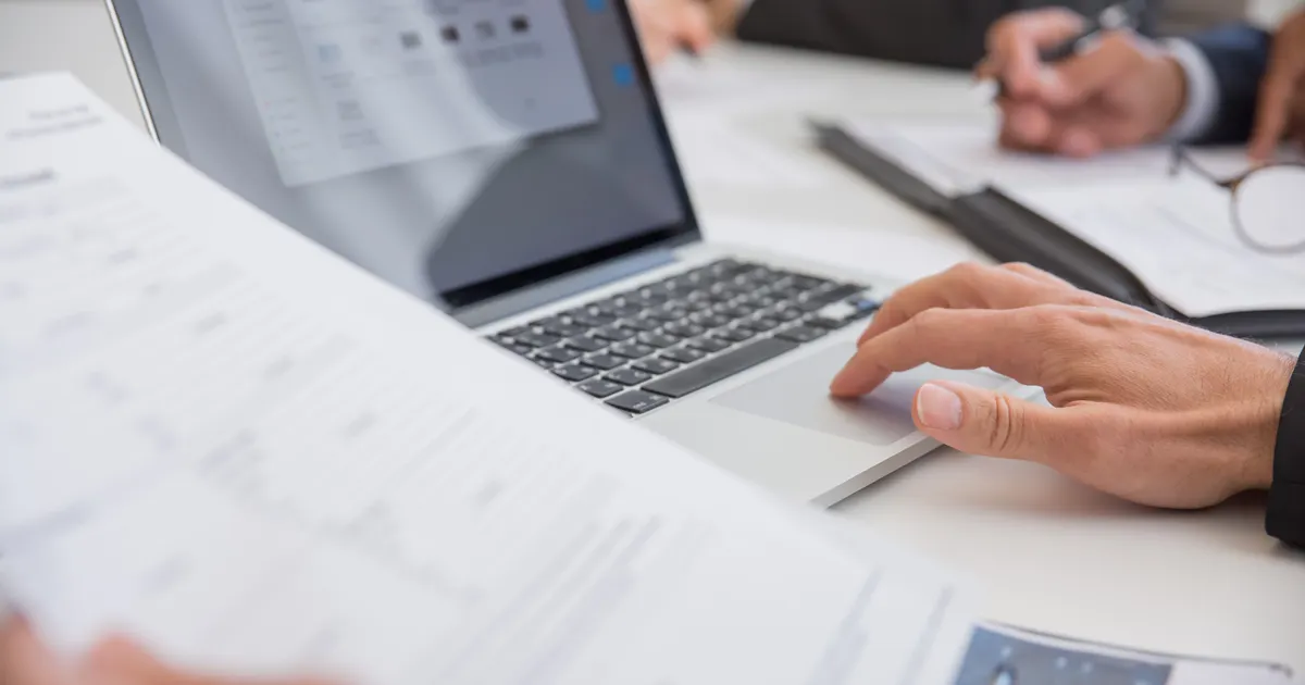 Socios revisando documentos en un computador portátil para modificar una sociedad en Empresa en un Día