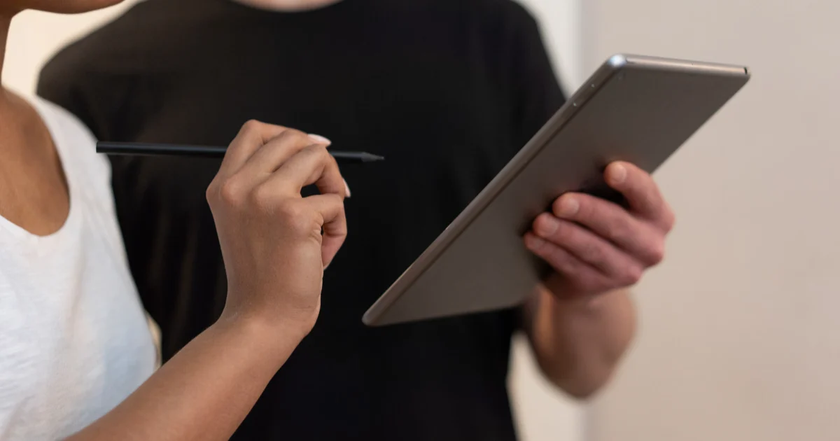 Una persona firma con lápiz en una tablet que le sostiene otra