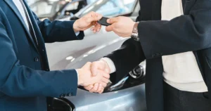 Dos personas se dan la mano y se entregan la llave de un auto